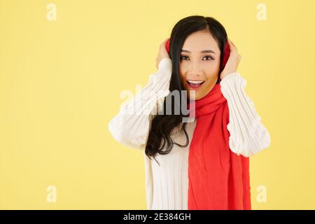 Portrait von aufgeregt junge asiatische Frau tragen Ohrenschützer und Warmer Wollschal für den Wintertag Stockfoto