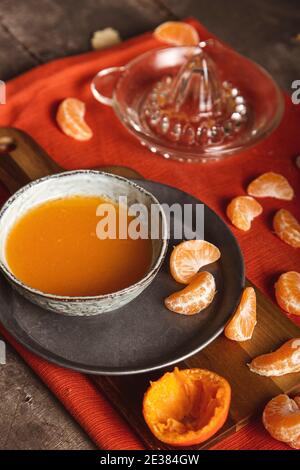 Saftig und frisch geschnittene Mandarine mit Saft auf Schneidebrett, Tischansicht. Stockfoto
