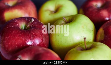 Mehrere leuchtend rote Äpfel und grüne Äpfel. Nahaufnahme von roten und grünen Äpfeln. Rote und grüne Äpfel in einer Reihe. Stockfoto