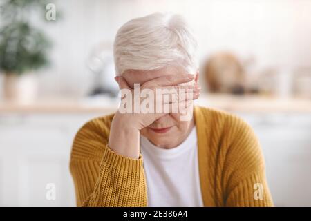 Ältere Frau, die an Migräne leidet, Küche innen Stockfoto