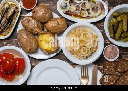 Einfaches rustikales ukrainisches Essen auf Holztisch, Nahaufnahme, Draufsicht. Vielfalt der gekochten Gemüse und Lebensmittel in Tellern, Ukraine Stockfoto