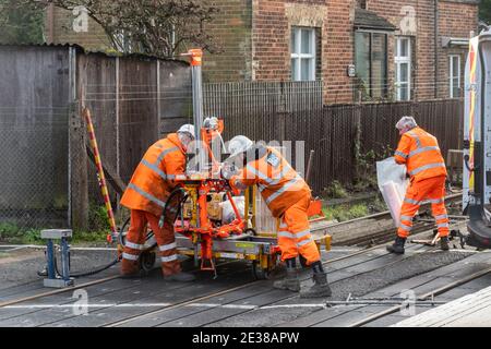 Arbeiter in orangefarbener Hochvisis-Kleidung, die an einer Bahnüberfahrt für AECOM und Resource Rail Ltd, Großbritannien, arbeiten Stockfoto