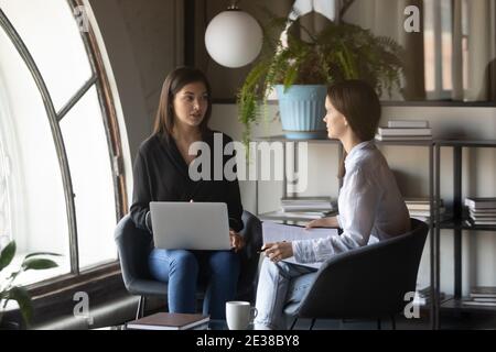 Indische Geschäftsfrau, die neue Angestellte unterrichtet, Laptop hält und die Aufgabe erklärt Stockfoto