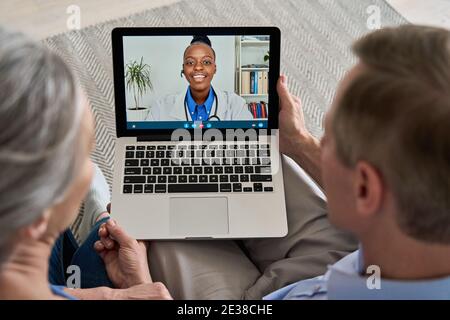 Über der Schulter Ansicht von alten Paar Patienten Video Anruf virtuellen Arzt auf Laptop. Stockfoto