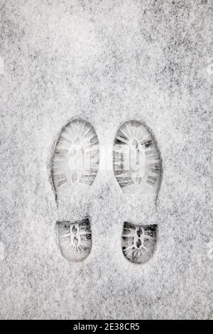 Zwei Schuhabdrücke nebeneinander im Neuschnee auf dem Bürgersteig. Stockfoto