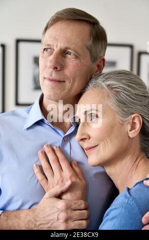 Reifer Ehemann umarmt lächelnde Frau mittleren Alters, träumen von einer guten Zukunft. Stockfoto