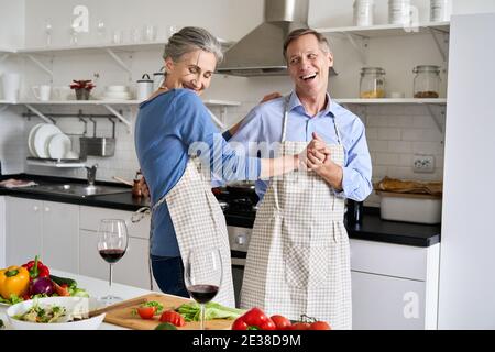 Happy ältere Paar tanzen in der Küche Vorbereitung gesunde Mahlzeit, Spaß haben. Stockfoto