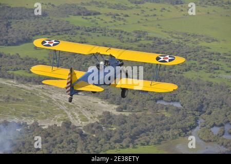 Ein 1940er Boeing N2S Stearman Doppeldecker in US Army Farben, mit Display Rauch. Stockfoto