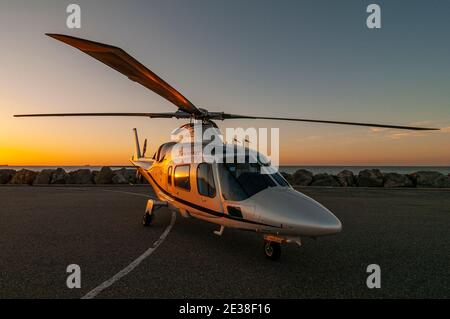 Ein Agusta 109 Power Executive Hubschrauber bei Sonnenuntergang. Stockfoto