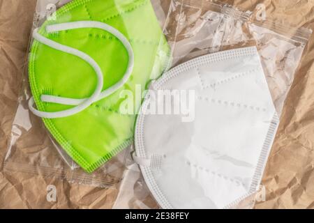 Zwei KN95 Atemschutzmasken in Plastiktüten auf einem zerknitterten Grunge-Krafthintergrund. Nahaufnahme. Grün-weiße Uniform. Apothekenkonz Stockfoto