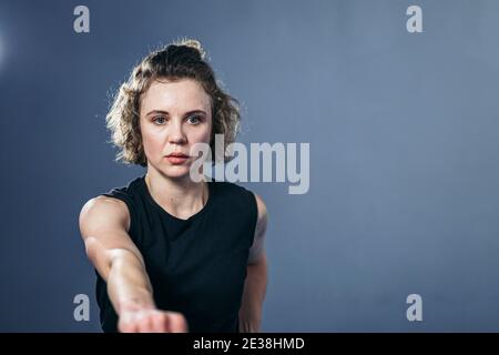 Kämpferin wirft Schläge direkt in die Kamera. Frau Athletin Taekwondo trifft scharf, schnelle Schläge, Blick direkt in die Kamera, schnelle Bewegung Stockfoto