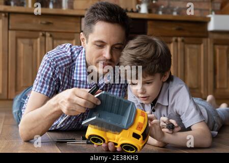 Liebevoller Vater haben Spaß spielen Reparatur Auto mit kleinen Sohn Stockfoto