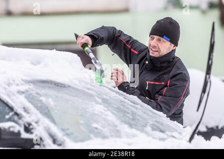 Männchen räumt Schnee von seinem Auto geparkt draußen nach starkem Schneefall in der Nacht. Stockfoto