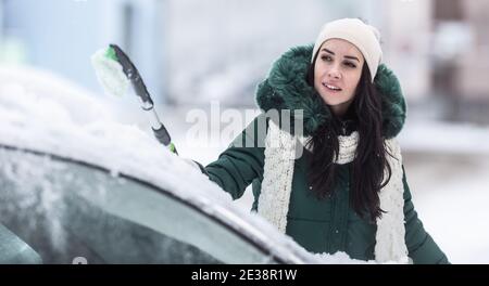 Auto Reinigung von Schnee an einem Wintertag durch eine weibliche Fahrer. Stockfoto