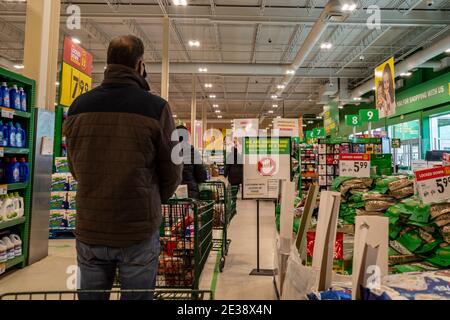 Ottawa, Ontario, Kanada - 17. Januar 2021: Kunden warten in der Schlange, um in einem Food Basics Lebensmittelgeschäft mit COVID-19-Pandemieregeln auszuchecken. Stockfoto