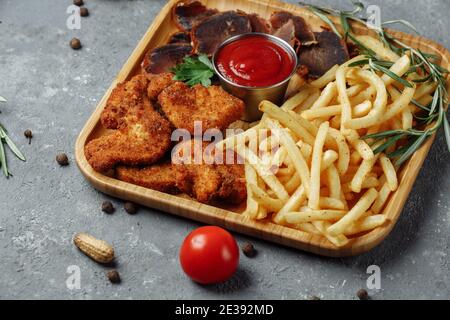 Teller mit Snacks. Panierte Hähnchennuggets, Bratkartoffeln und Jamon Stockfoto