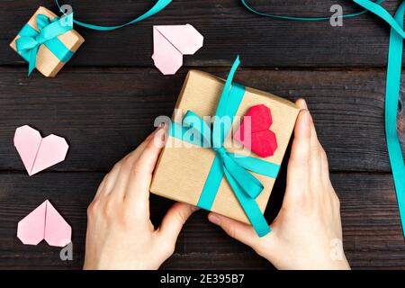 Weibliche Hände halten eine schöne Geschenkbox. Flach Liegend. Blick von oben. Geschenkverpackung. Stockfoto