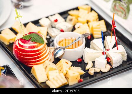 Sortiment von Käse mit Honig und Nüssen auf einem modernen Schneidebrett Stockfoto