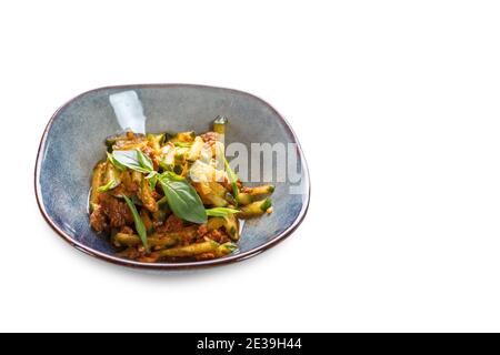 Eine Schüssel mit in Scheiben geschnittenen Gurken, Fleisch in Soße und Salatblättern auf einem weißen isolierten Hintergrund. Stockfoto