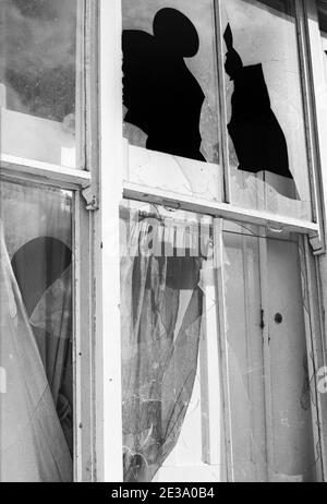 Großbritannien, West London, Notting Hill, 1973. Heruntergekommene und heruntergekommene, große, vierstöckige Häuser werden langsam restauriert und neu dekoriert. Kaputtes Fensterglas im Haus neben dem Talbot Tabernacle Seiteneingang in Powis Gardens Stockfoto