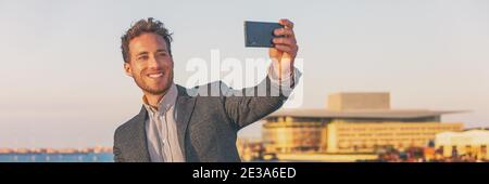 Telefon mit Geschäftsmann Selfie mit Handy auf Reise Geschäftsreise außerhalb zu Fuß in der Stadt Banner Panorama. Junger kaukasischer Erwachsener in seinem Stockfoto