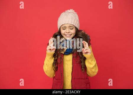 Teen Kind in Kugelweste und Strickmode machen Wunsch. Saisonale Kindermode. weihnachtsurlaub und Urlaub. Nette Schönheit warm halten. Wettervorhersage. Fröhliches Mädchen bereit für Winteraktivitäten. Stockfoto