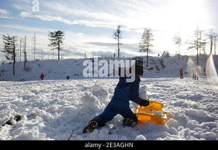 Skrzyczne, Polen - 17. Januar 2021: Ein kleiner Junge reitet auf dem Schlitten auf dem Gipfel des Skrzyczne in den Schlesischen Beskiden Stockfoto