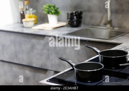 Moderne Küche mit Antihaft-Kochtöpfen auf einem Induktionsherd. Selektiver Fokus. Stockfoto