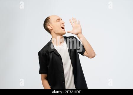 Porträt eines jungen halbkahlen Mannes in schwarzem Hemd mit weißem T-Shirt darunter. Aufgeregt jungen Erwachsenen glücklich Mann zeigt Zufriedenheit mit den Händen Stockfoto