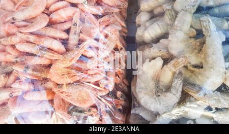 Zwei große Plastiktüten mit gefrorenen rohen und gekochten Garnelen, auf der Theke des Fischmarktes. Stockfoto