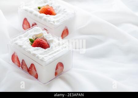 Erdbeer-Shortcake in Kunststoffbox auf mit Stoffhintergrund und Kopierraum, Minimal-Kuchen und Bäckereikonzept Stockfoto