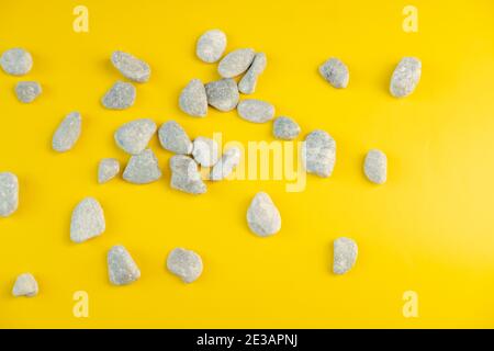 Sommer Design Hintergrund mit kleinen Steinen auf Papier mit hartem Licht. Trendfarbe von 2021 gelb, leuchtend gelb und ultimativ grau. Stockfoto