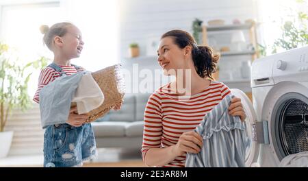 Schöne junge Frau und Kind Mädchen kleinen Helfer haben Spaß und Lächeln, während die Wäsche zu Hause. Stockfoto