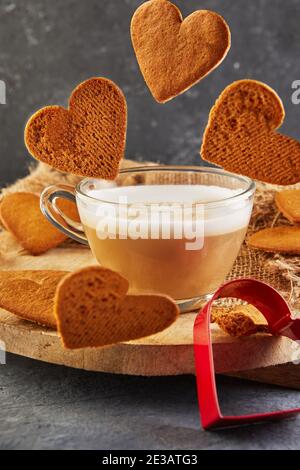 Herzförmige Lebkuchenkekse fallen in eine Tasse Kaffee Stockfoto