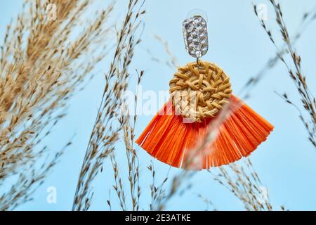 Natürliches handgemachtes Produkt, ein Paar Ohrringe auf dem Hintergrund des goldenen Schilfgrases. Umweltfreundliches und nachhaltiges Konzept. Umweltfreundliche Einkaufsmöglichkeiten und Stockfoto