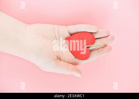 Weibliche Hand mit Holzherz. Rotes Herz als Symbol für Valentinstag, Wohltätigkeit oder Spende. Gesundheit, Liebe und Unterstützung, Organspende, Familie Stockfoto