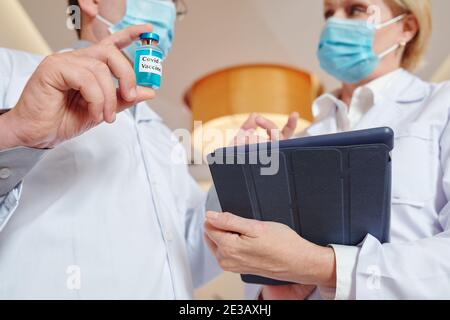 Nahaufnahme der Forschung sie mit Fläschchen und Tablet-Computer diskutieren Verfahren für neue Impfstofftests Stockfoto
