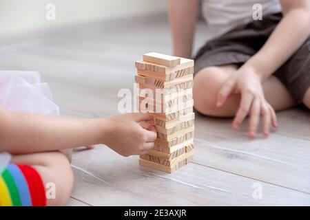 Zwei Kinder sammelt einen Turm aus Holzblöcken auf dem Boden. Stockfoto