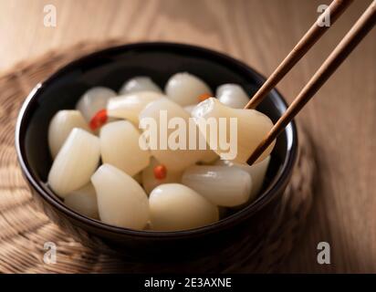 Japanisches Rakkyo mit Essstäbchen auf einem hölzernen Hintergrund halten Stockfoto