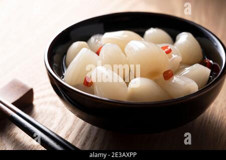 Japanische Rakkyo und Essstäbchen auf einem hölzernen Hintergrund platziert Stockfoto