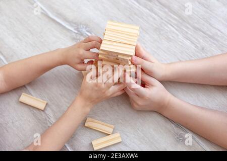 Kinderhände sammelt einen Turm aus Holzblöcken auf dem Boden. Stockfoto