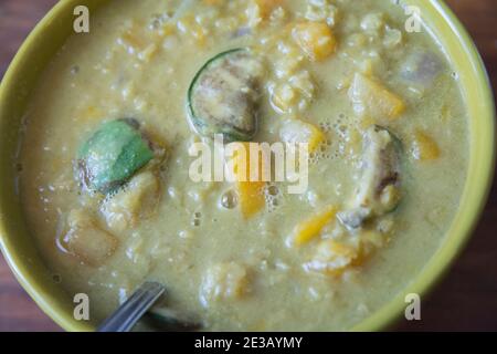 Asiatische Linsen und Butternut-Kürbissuppe, mit thailändischen Auberginen, in einer grünen Schüssel serviert Stockfoto