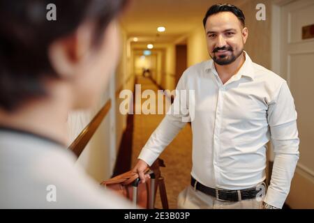 Portrait von fröhlichen reifen Mann mit Koffer im Gespräch mit Manager Im Hotelflur Stockfoto