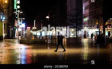 Hannover, Deutschland. Januar 2021. Ein Mann geht am frühen Morgen durch das verlassene Stadtzentrum. Eine landesweite nächtliche Ausgangssperre wird wahrscheinlich in den Gesprächen der Bundesländer über eine mögliche weitere Verschärfung der Maßnahmen zur Eindämmung der Corona-Pandemie in Betracht gezogen werden. Kredit: Julian Stratenschulte/dpa/Alamy Live Nachrichten Stockfoto