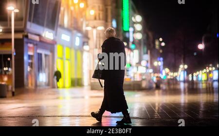 Hannover, Deutschland. Januar 2021. Eine Frau geht am frühen Morgen durch das verlassene Stadtzentrum. Eine landesweite nächtliche Ausgangssperre wird wahrscheinlich in den Gesprächen der Bundesländer über eine mögliche weitere Verschärfung der Maßnahmen zur Eindämmung der Corona-Pandemie in Betracht gezogen werden. Kredit: Julian Stratenschulte/dpa/Alamy Live Nachrichten Stockfoto