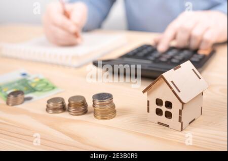 Hypothekendarlehenrechner. Männliche Hand legen Münzstapel Geld Treppe auf Tisch, Business Growth Concept, Stapel von Münzen auf Holztisch mit Kalkül Stockfoto