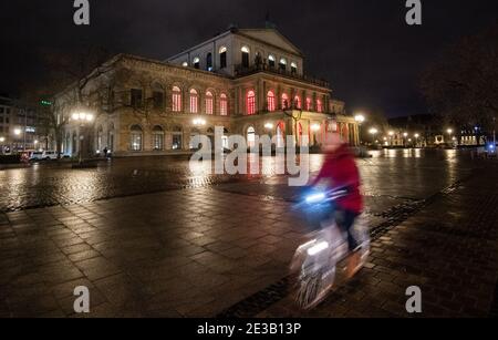 Hannover, Deutschland. Januar 2021. Am frühen Morgen fährt eine Frau mit dem Fahrrad über den verlassenen Opernplatz. Eine landesweite nächtliche Ausgangssperre wird wahrscheinlich in den Gesprächen der Bundesländer über eine mögliche weitere Verschärfung der Maßnahmen zur Eindämmung der Corona-Pandemie in Betracht gezogen werden. Kredit: Julian Stratenschulte/dpa/Alamy Live Nachrichten Stockfoto