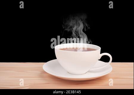 Weiße Tasse mit heißem Tee auf Holztisch isoliert auf schwarzem Hintergrund. Seitenansicht. Porzellan weiße chinesische Tasse schwarzen Tee und Untertasse auf Vintage-Holz Stockfoto