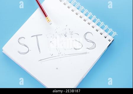 Stresskonzept. Wort Stress schreiben auf Notizbuch. Bleistift mit Radiergummi Striche Wort Stress. Reduzieren, Linderung und Management Stress Konzept. Blauer Hintergrund Stockfoto