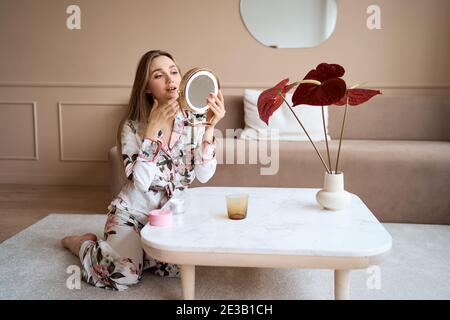 Attraktive Frau im Schlafanzug Anwendung Gesichtscreme. Attraktive junge Frau in Pyjama Anwendung feuchtigkeitsspendende Creme auf das Gesicht. Frisch vom Morgen Stockfoto